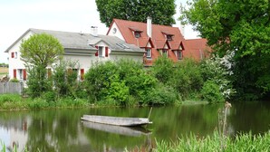 A house with a red roof and a small dock by a calm lake.