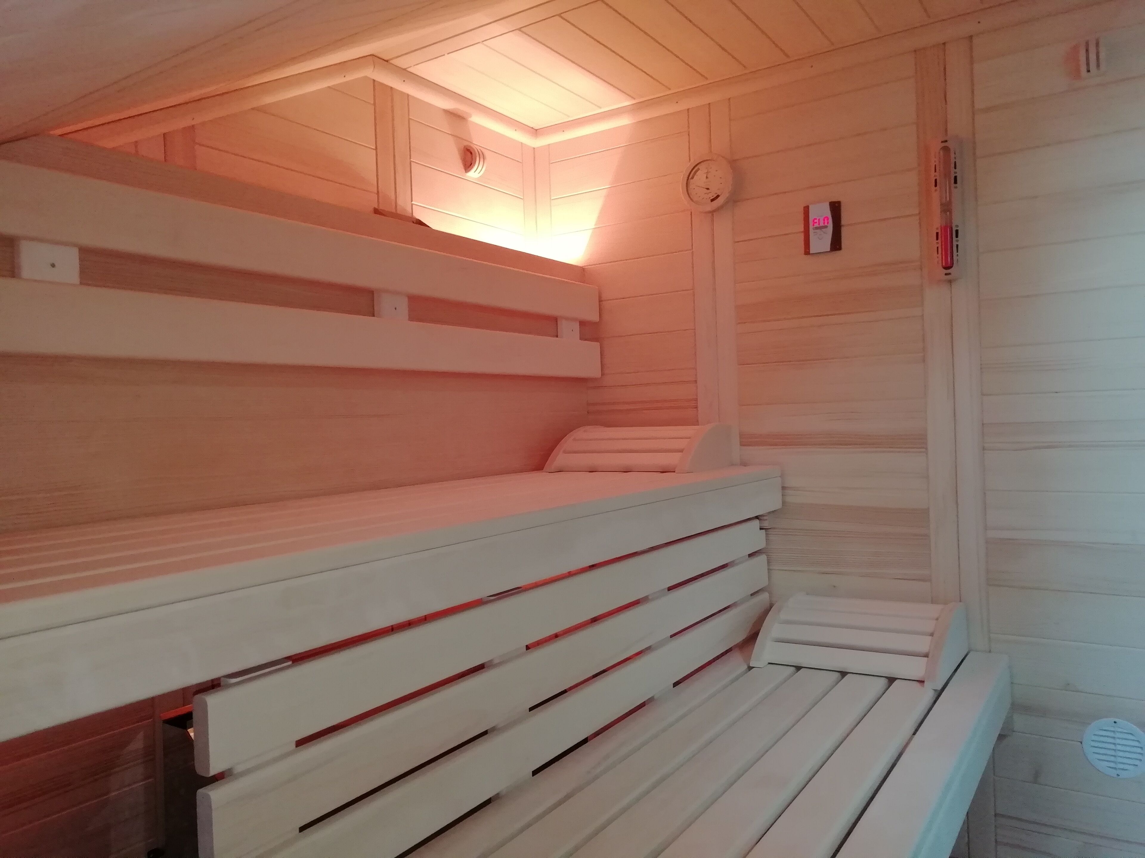 Una sauna con bancos de madera y un reloj en la pared.
