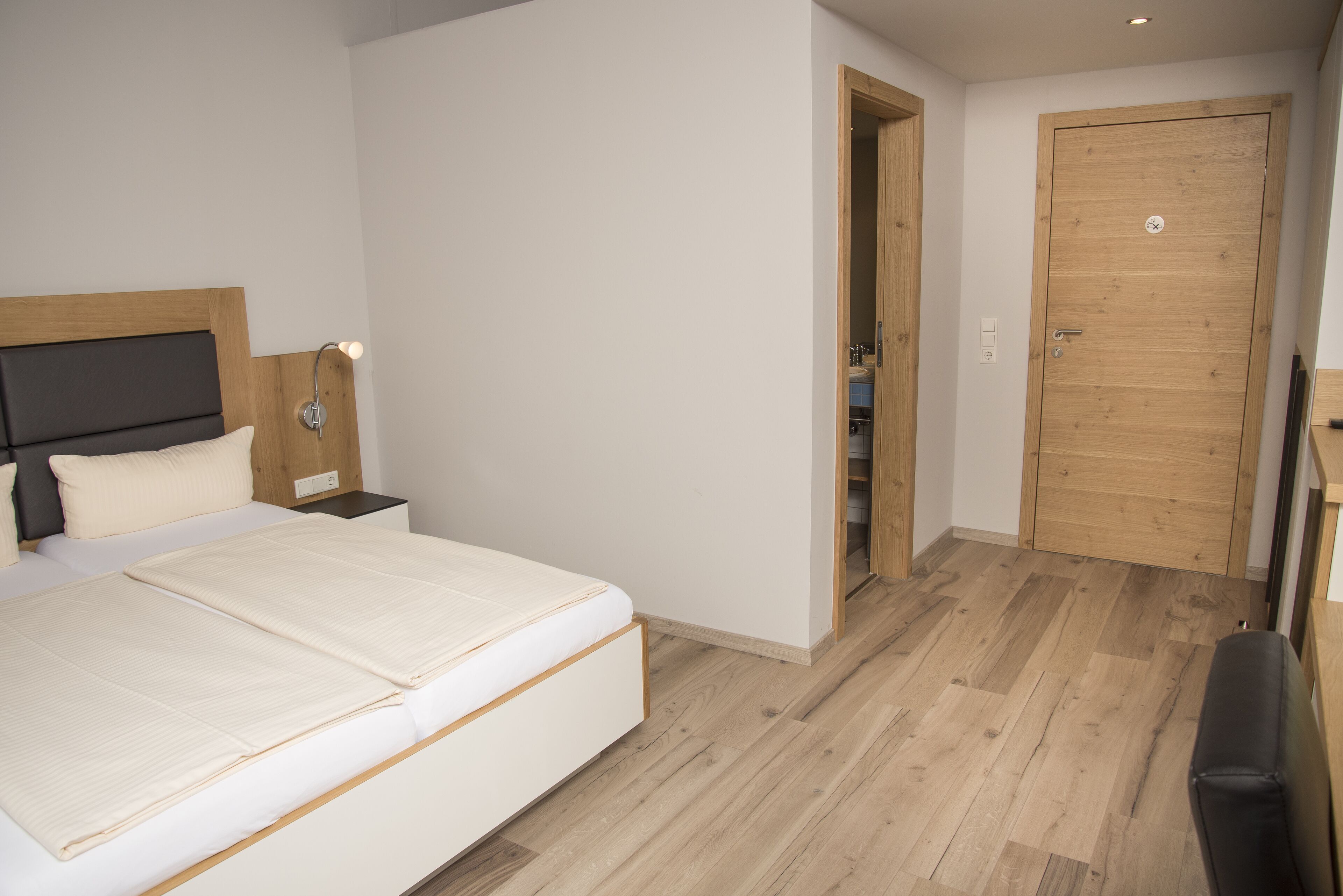 Um quarto com uma cama, mesas de cabeceira, uma porta de madeira e um armário.