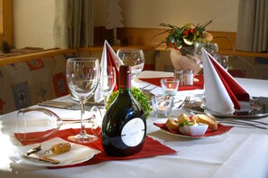 Une table à manger dressée avec des verres à vin, une bouteille de vin et une assiette de pain et de beurre.