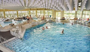 An indoor swimming pool with multiple lanes, stone steps, and a sunlit area with lounge chairs. - Gasthof Zum Goldenen Lamm (Treuchtlingen)