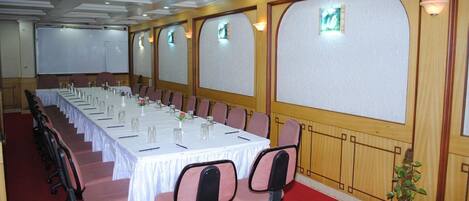A conference room with a long table, chairs, and a projector screen.