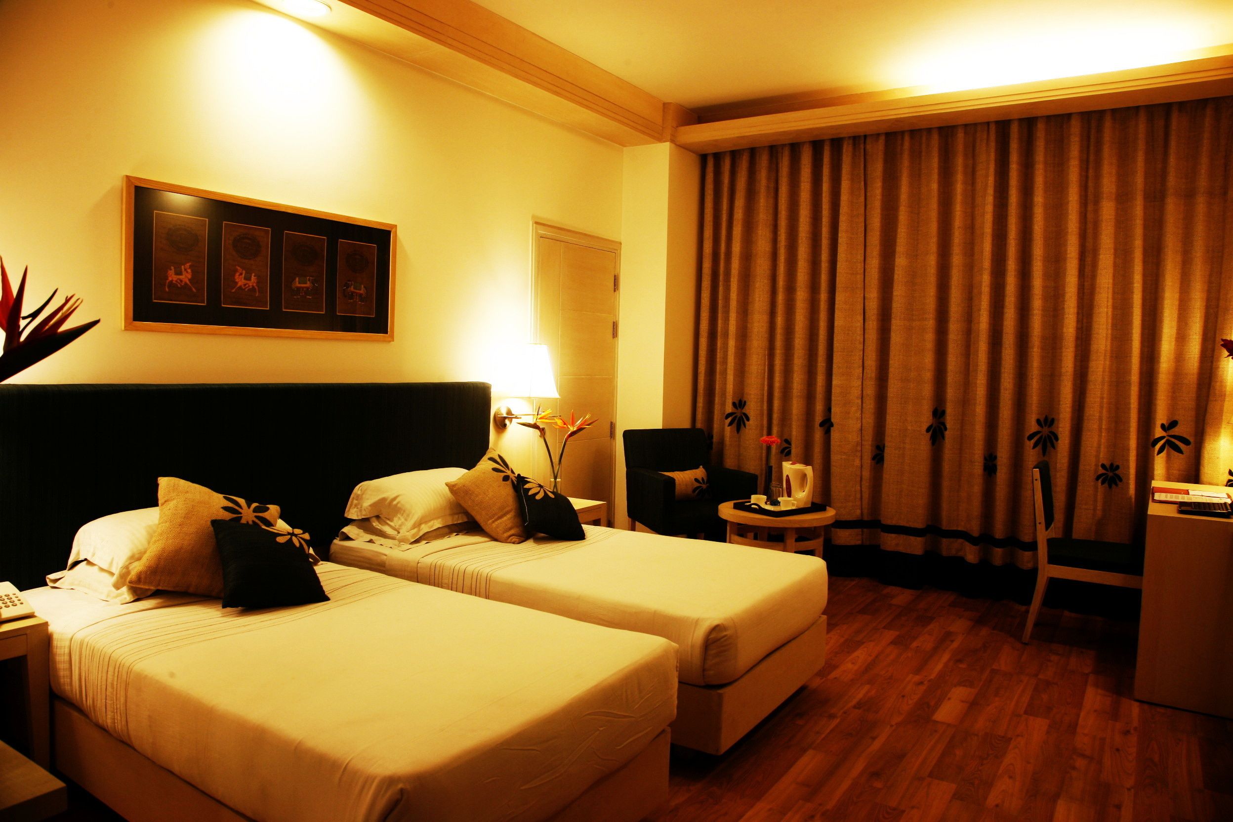 Une chambre d’hôtel avec deux lits, un bureau, une chaise, une lampe et un rideau.