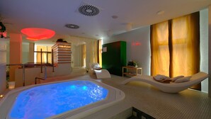 A modern spa room with a hot tub, a lounge chair, and a massage table.