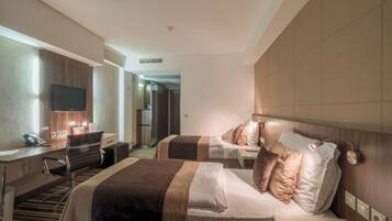 A hotel room with two beds, a desk, a chair, a TV, and a bathroom visible in the background.