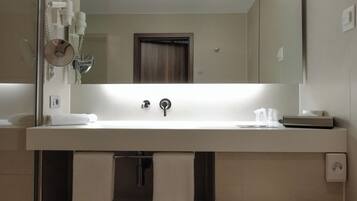 A modern bathroom with a white sink, a mirror above it, a toilet, and a shower area.