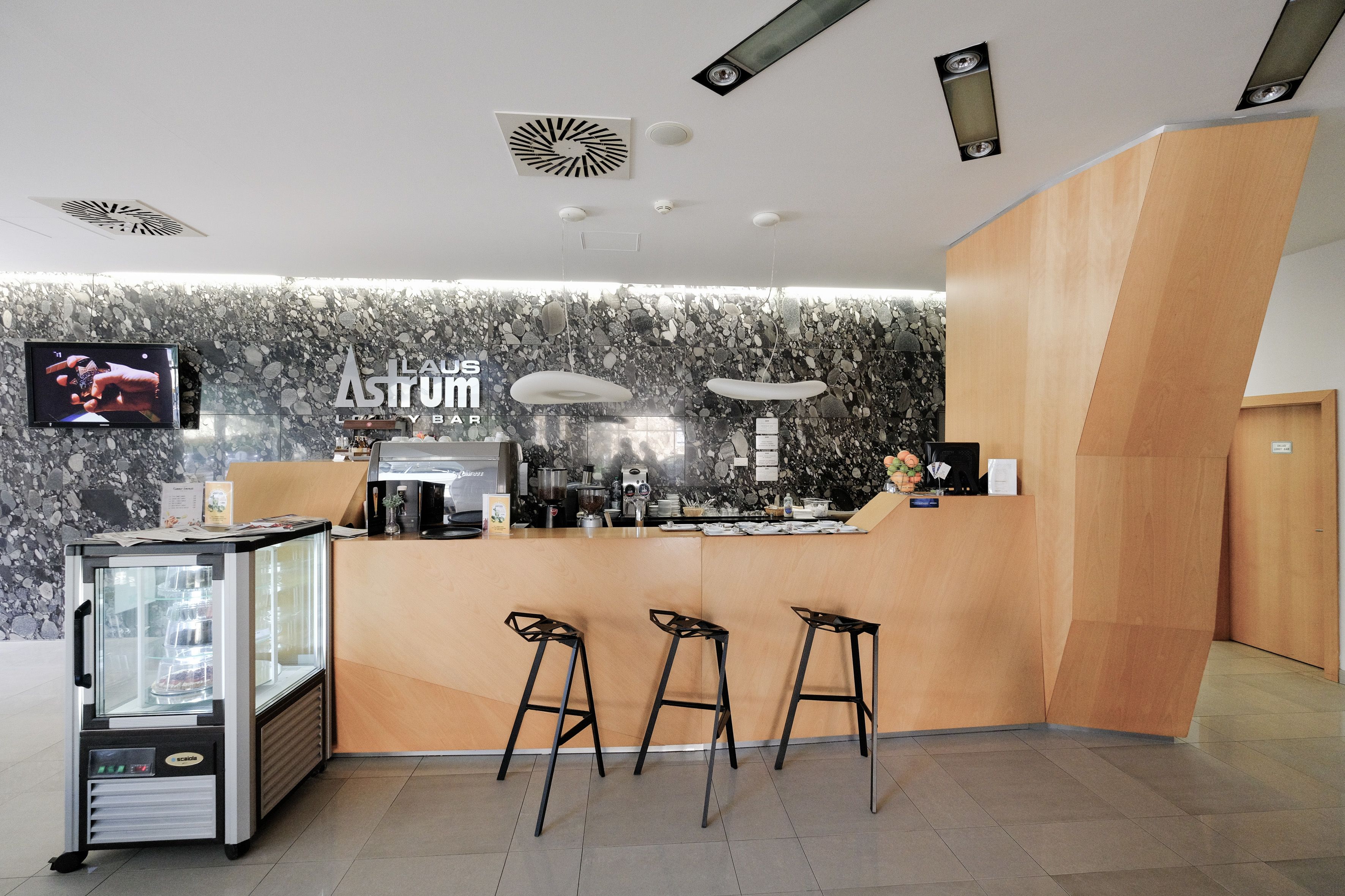 A modern bar area with a marble wall, a counter, and three stools.