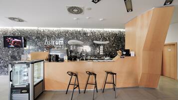 A modern bar area with a marble wall, a counter, and three stools.