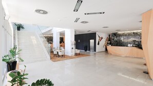 A modern hotel lobby with a reception desk, a staircase, and seating area.