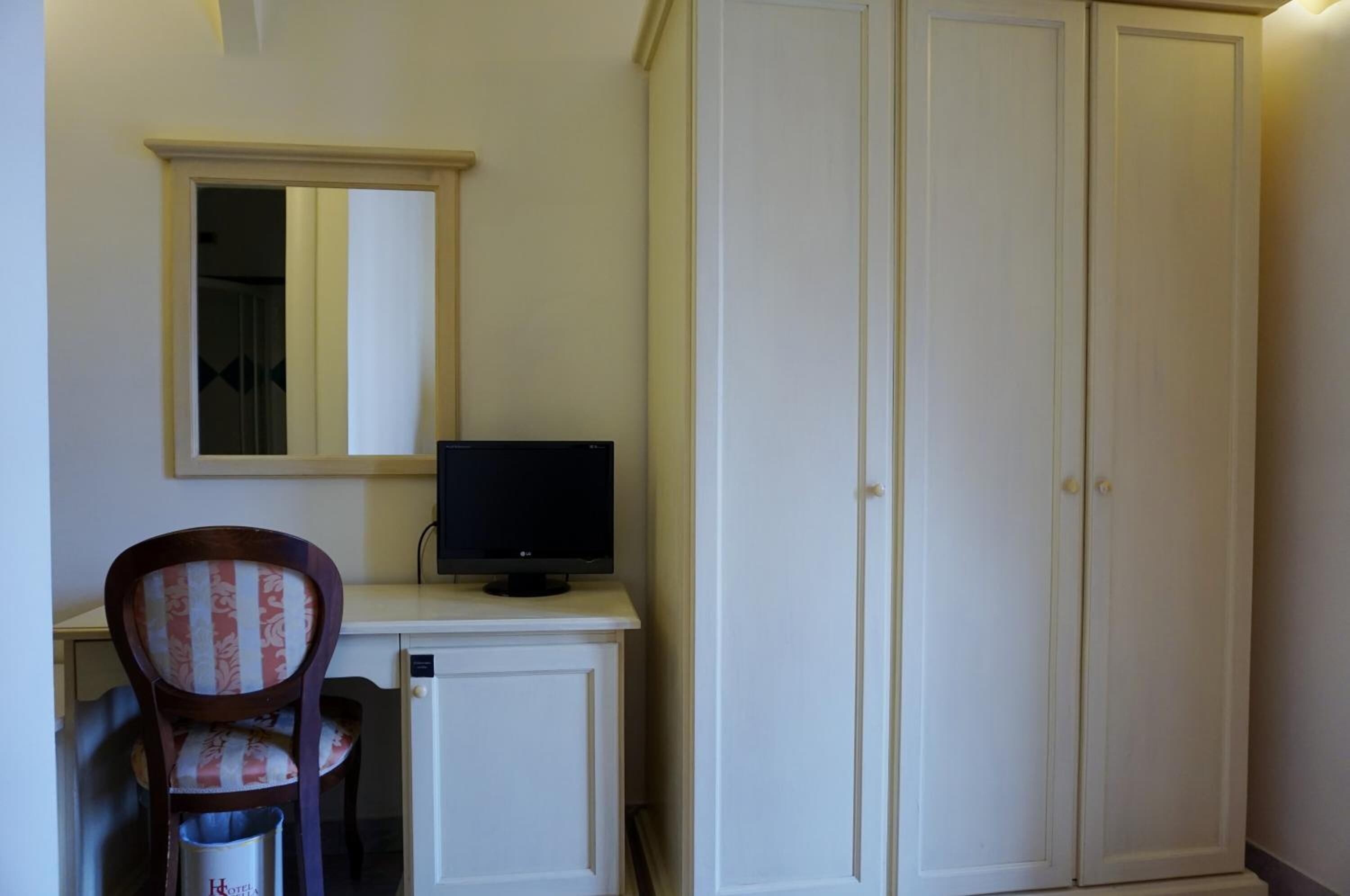 Een kamer met een bureau, een stoel, een televisie en een kledingkast.