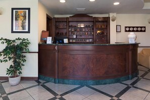 A reception desk with a marble top, surrounded by a display of various items and a potted plant. - Hotel Ristorante Stella 2000 (Olbia)