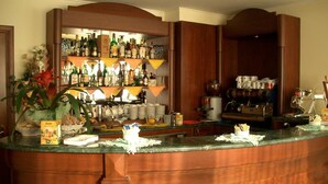 A bar area with a wooden counter, shelves with bottles, and a coffee machine. - Hotel Ristorante Stella 2000 (Olbia)