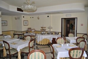 A dining area with multiple tables, chairs, and a chandelier. - Hotel Ristorante Stella 2000 (Olbia)