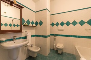 Un bagno con lavandino, bidet, WC e vasca da bagno.