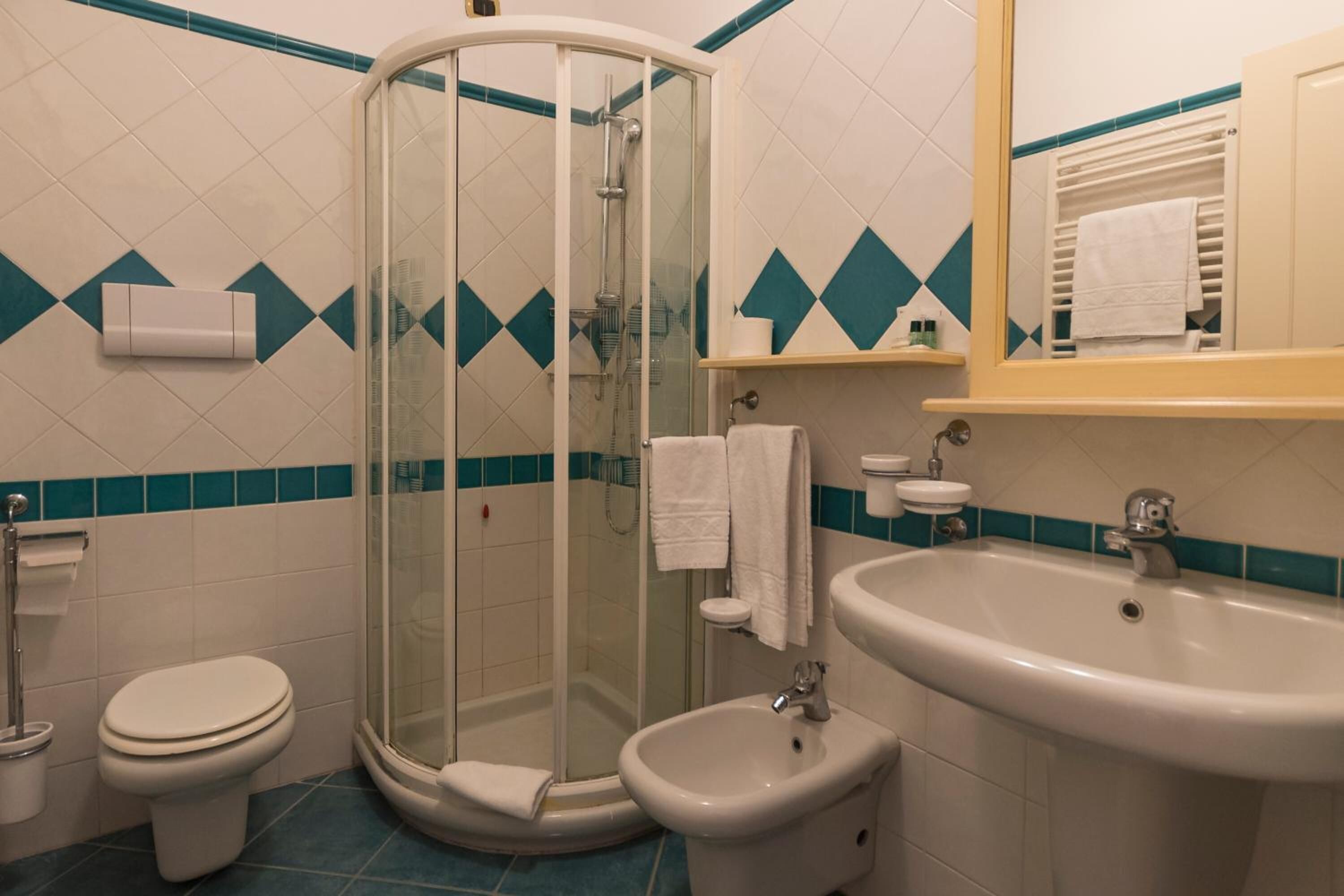 Une salle de bain avec une douche à parois de verre, des toilettes, un lavabo et un miroir.
