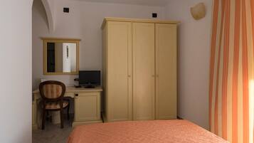 A bedroom with a bed, a desk with a computer, a chair, and a wardrobe.