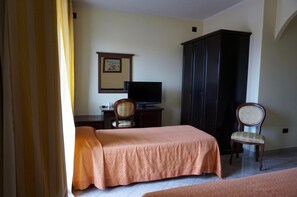 A hotel room with a bed, a desk with a television, a wardrobe, and two chairs. - Hotel Ristorante Stella 2000 (Olbia)