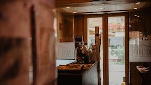 A reception desk with a glass enclosure, a wooden counter, and a view of the outside through a glass door.