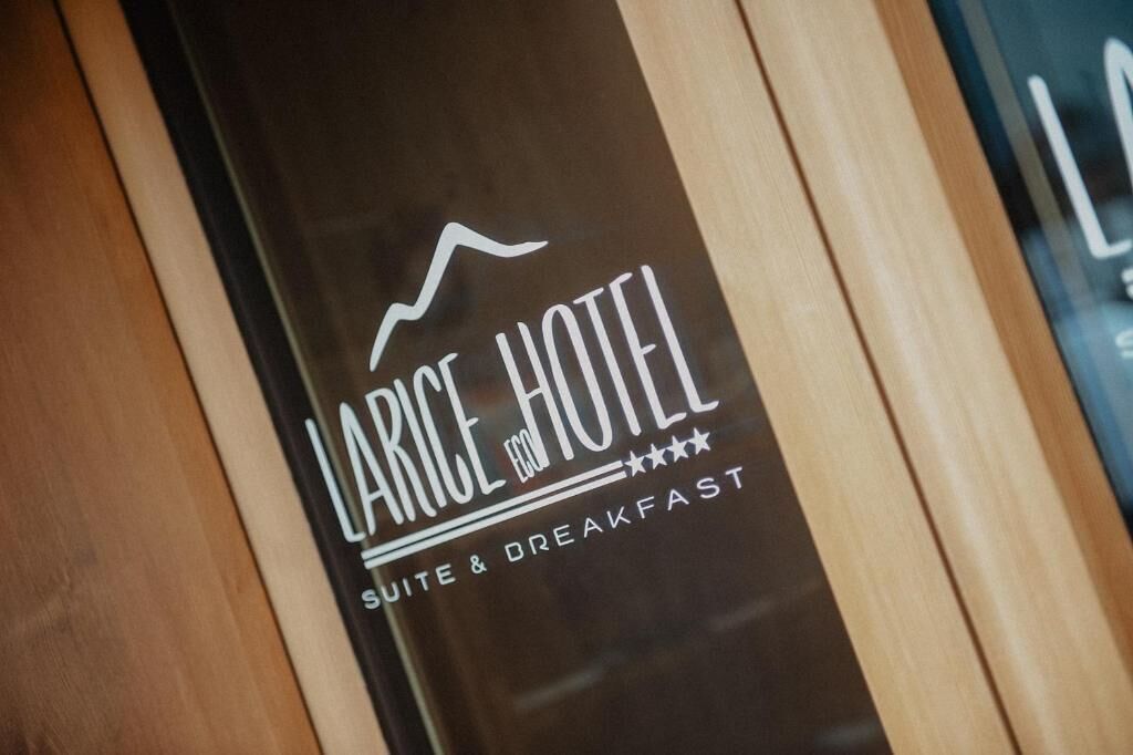 Placa do HOTEL LARICE, indicando que oferece suíte e café da manhã.