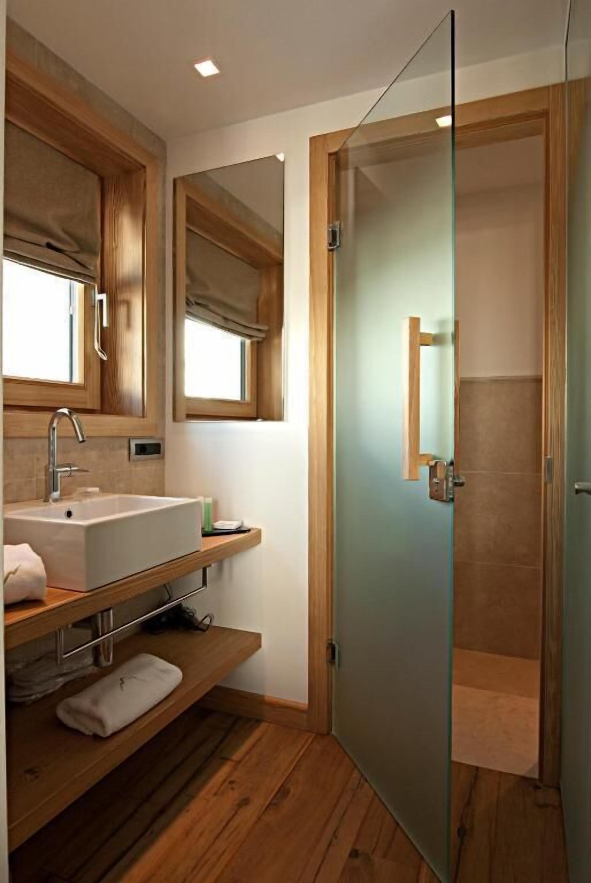 A modern bathroom with a wooden vanity, a glass shower enclosure, and a large mirror.