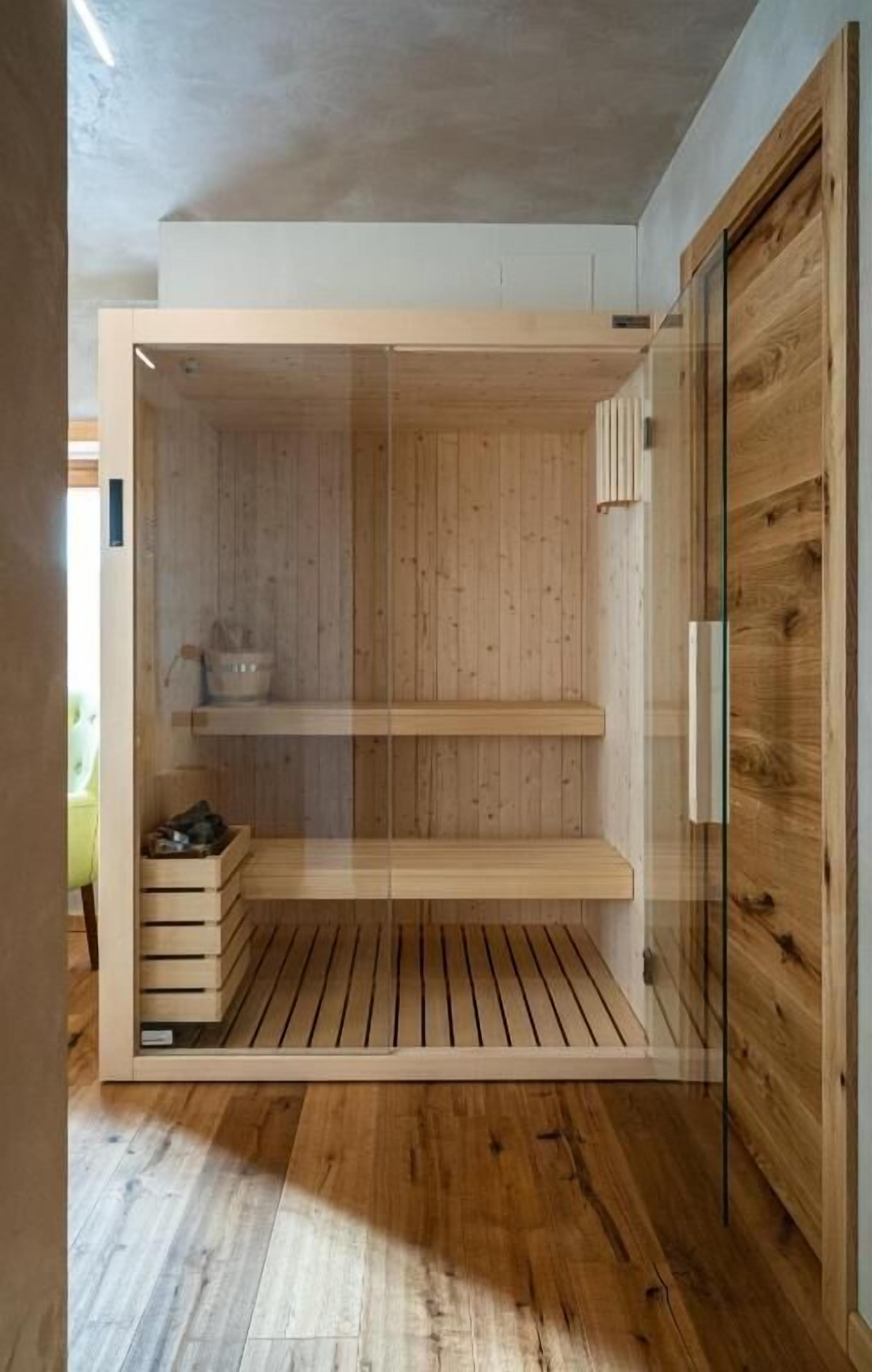 A modern room with wooden flooring, a built-in bench, and a glass door.