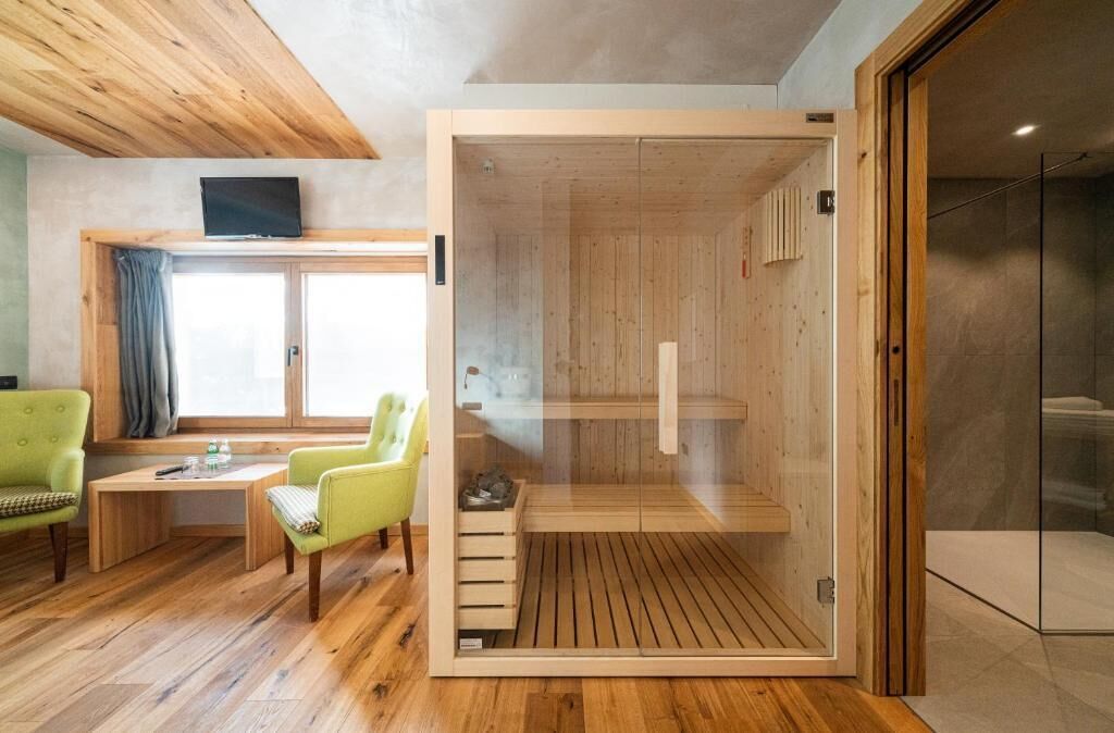 A modern room with a wooden sauna, a wooden table with chairs, and a large window with curtains.