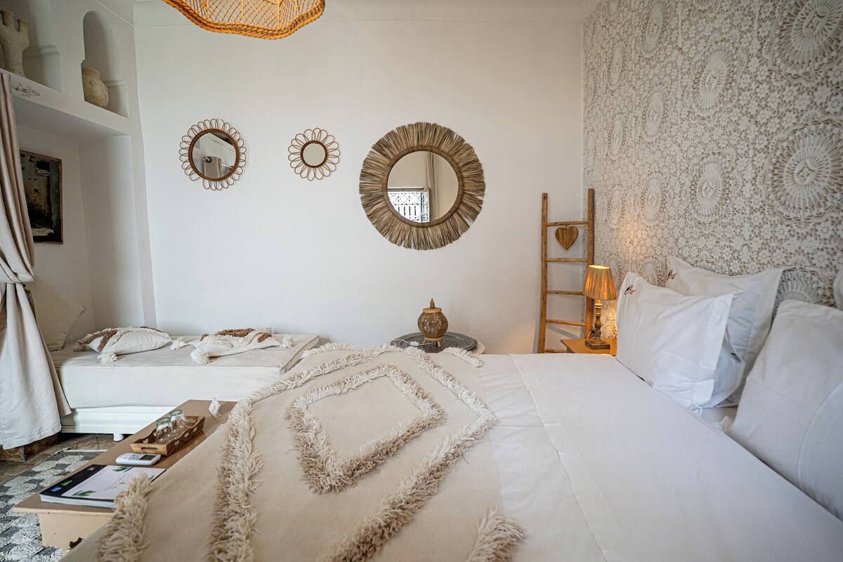 A bedroom with a bed, bedside tables, a lamp, and decorative mirrors on the wall.