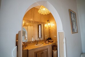 Un baño con un espejo grande, tocador de madera y una lámpara decorativa.