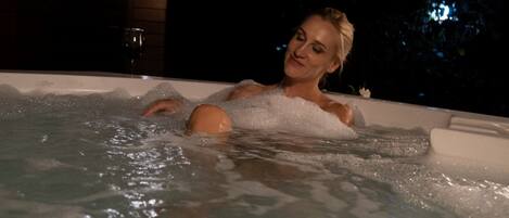 Una persona en un jacuzzi con burbujas y agua visibles.