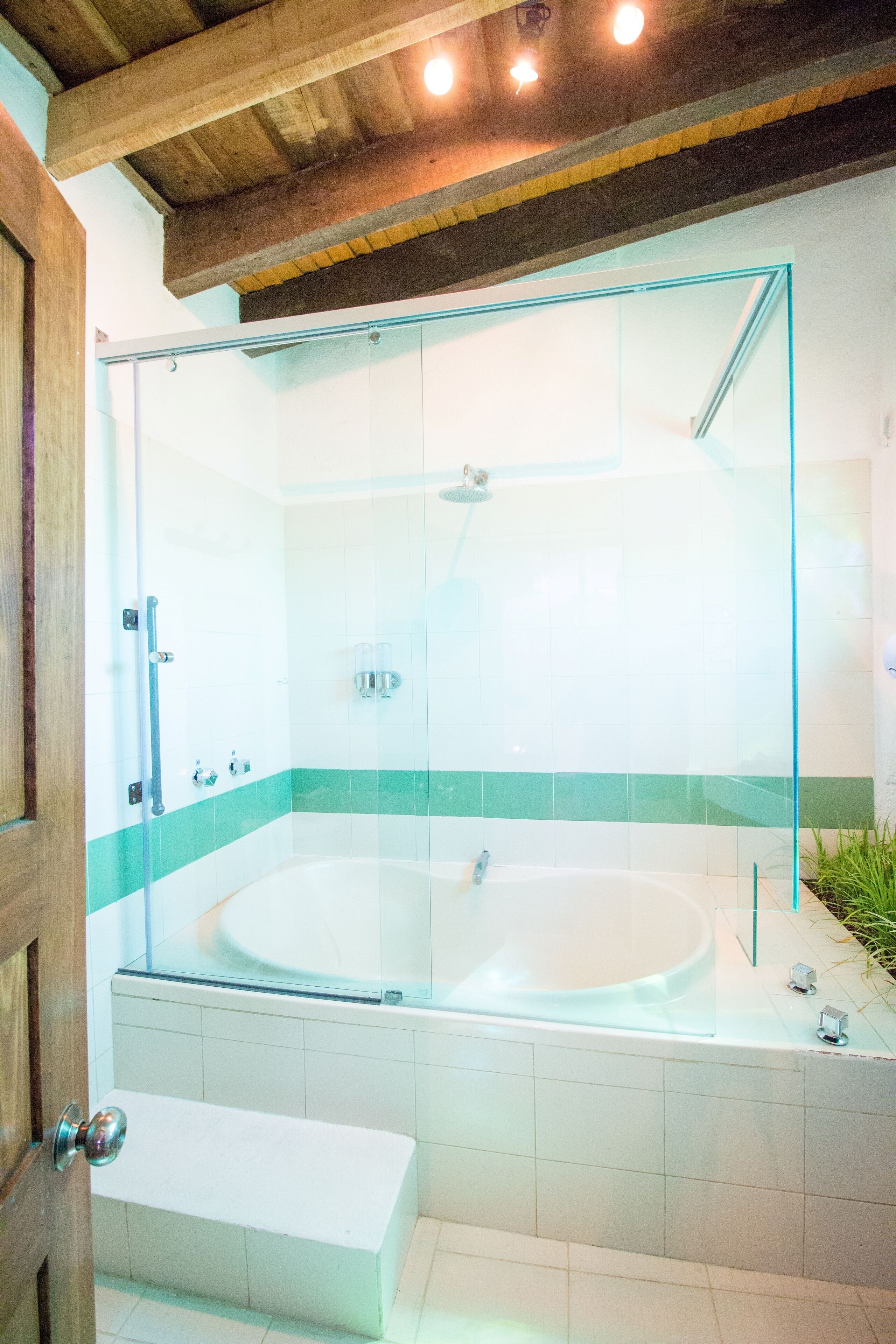 Un baño moderno con ducha envuelta en cristal, una bañera independiente y un banco.