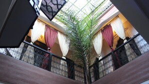 Un interior de varios niveles con un atrio central, que presenta una escalera con barandillas de hierro forjado y una planta grande en maceta.