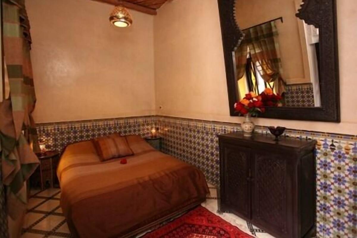 A bedroom with a bed, a dresser, a mirror, and a tiled wall.