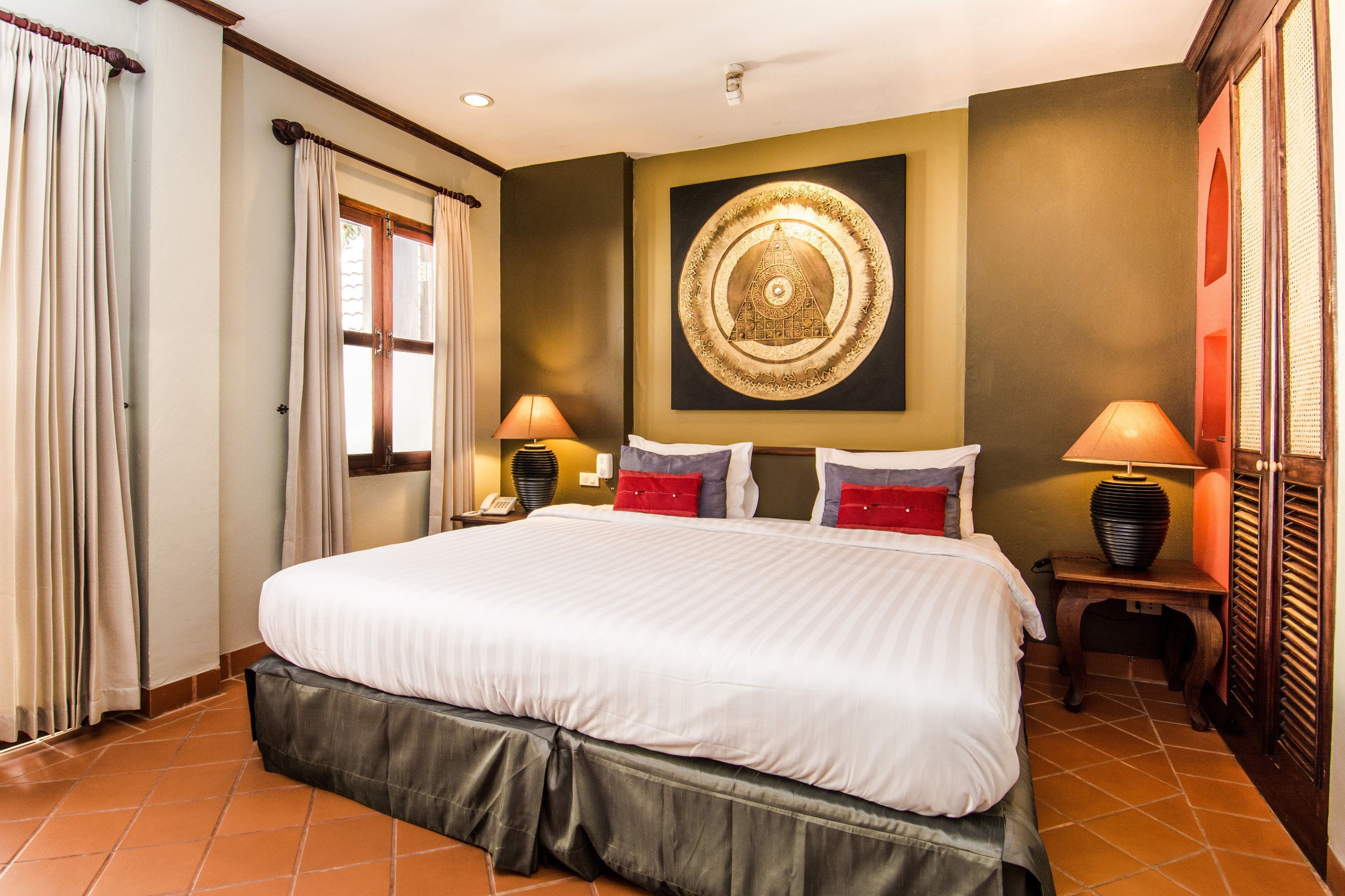 A hotel room with a large bed, two bedside tables with lamps, a wall art piece, and a window with curtains.