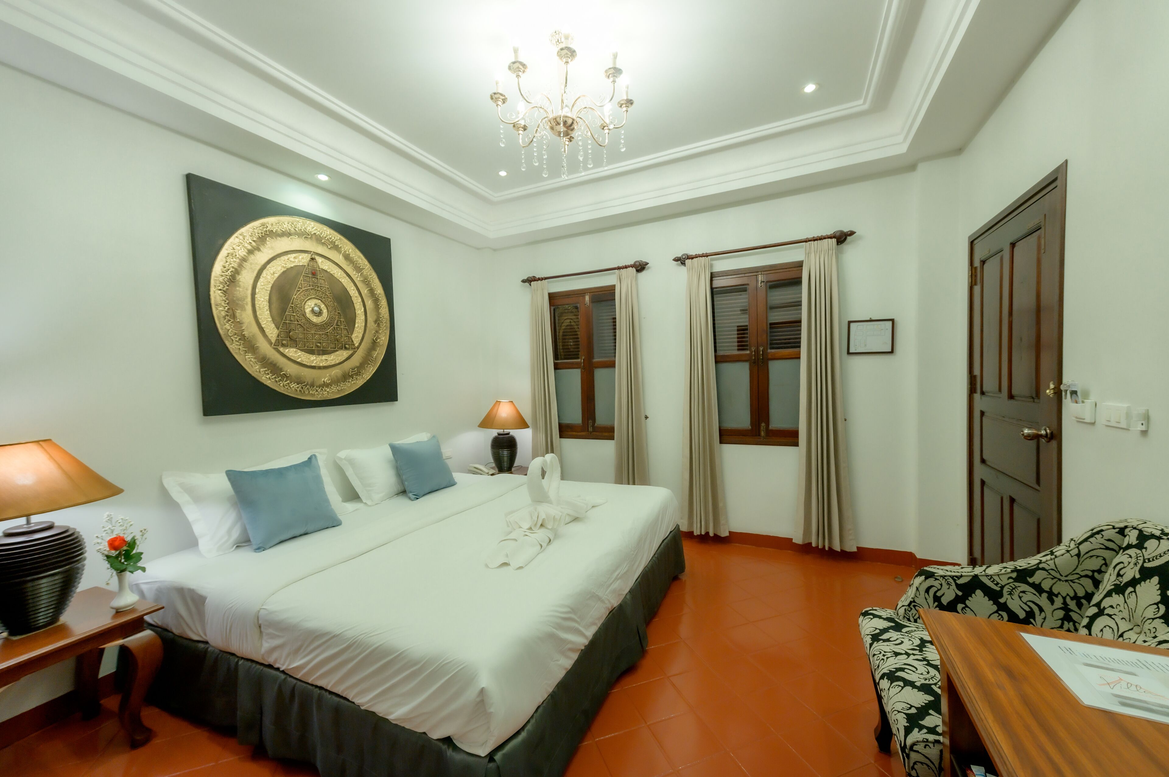 Una habitación de hotel con una cama grande, una araña de cristal, una obra de arte en la pared y un sofá.