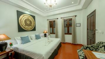 Una habitación de hotel con una cama grande, una araña de cristal, una obra de arte en la pared y un sofá.