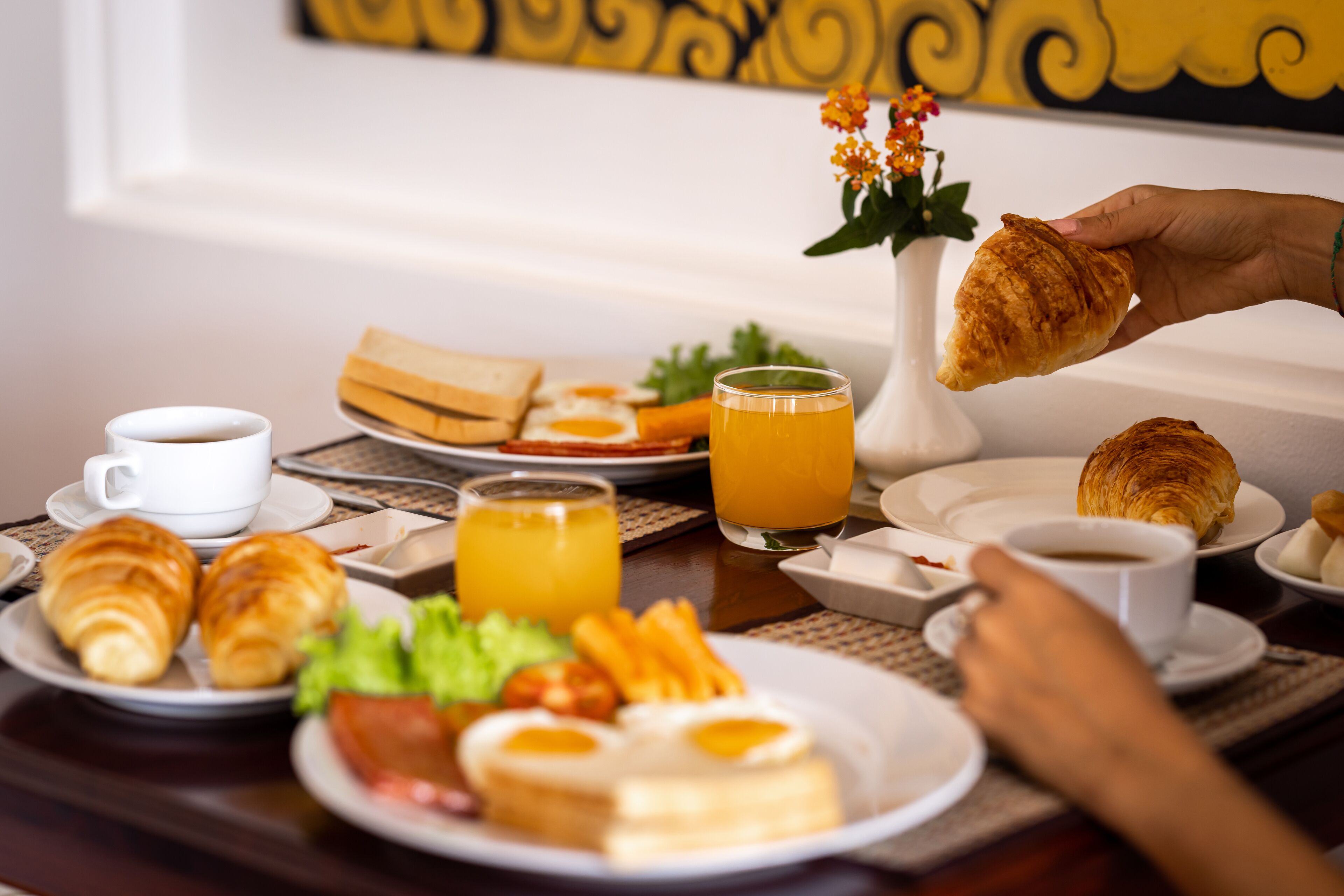 Un desayuno con cruasanes, huevos y zumo de naranja sobre una mesa.