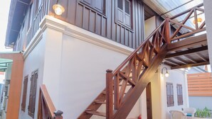 A wooden staircase leading to a second floor with a metal roof and hanging lights. - Villa Deux Rivieres (Luang Prabang)