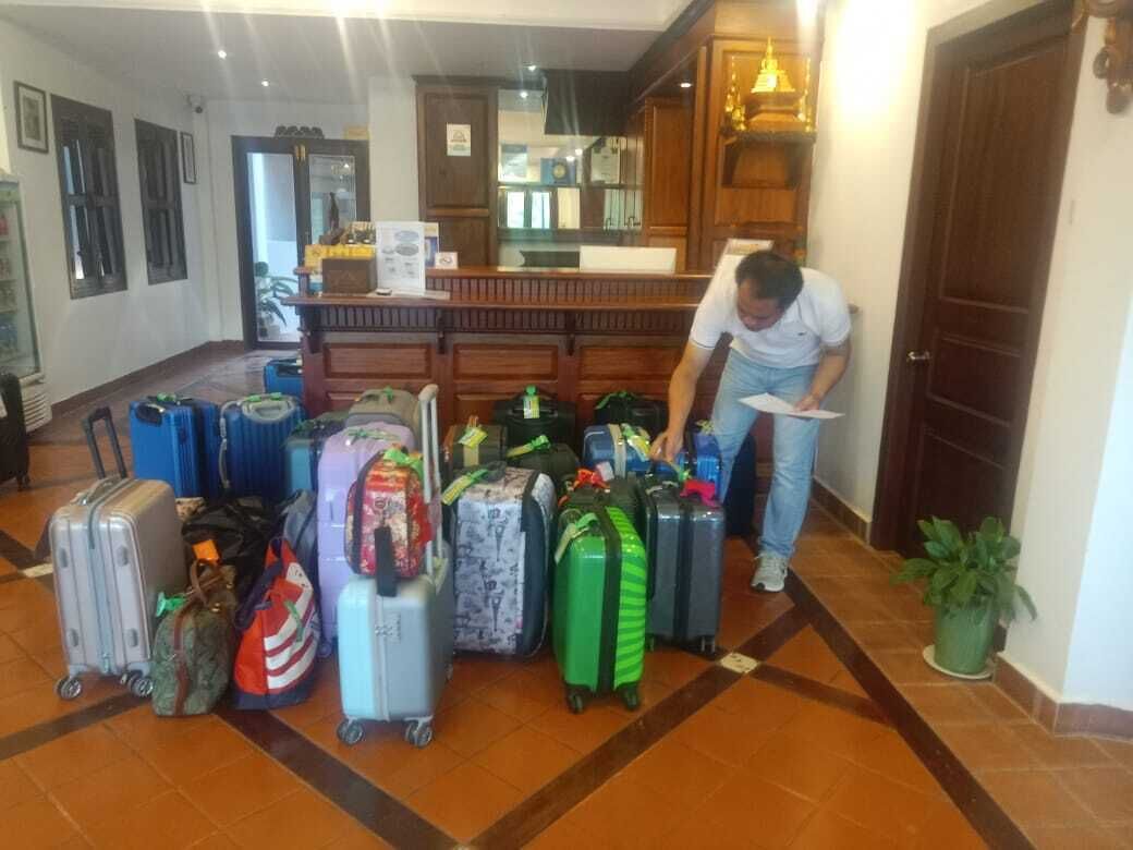 A hotel lobby with multiple suitcases and a person bending over a piece of paper.
