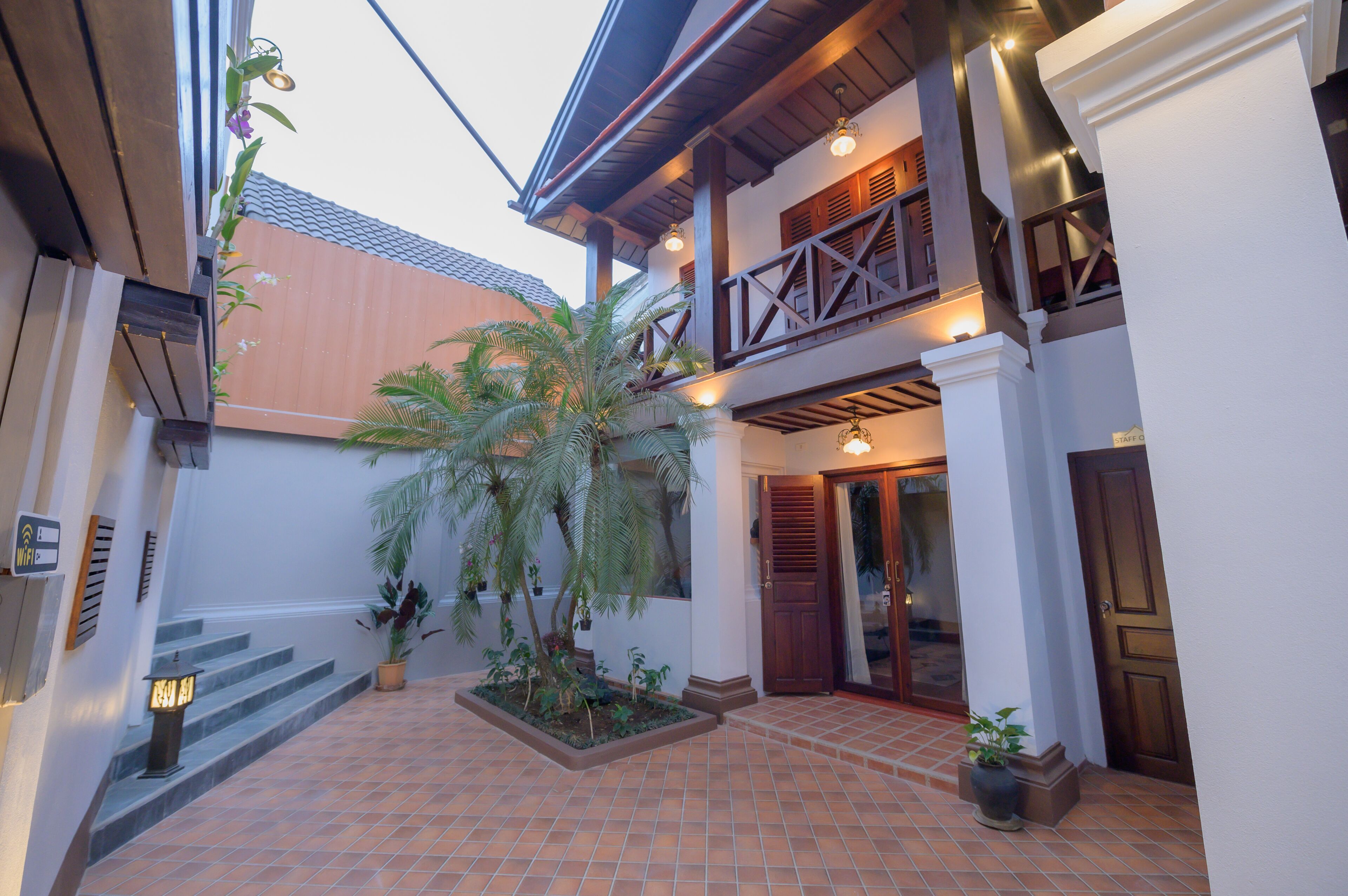 A courtyard with a palm tree, potted plants, and a staircase leading to an upper level.