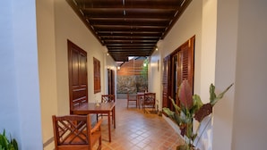 A corridor with wooden doors, a stone wall, and a tiled floor. - Villa Deux Rivieres (Luang Prabang)