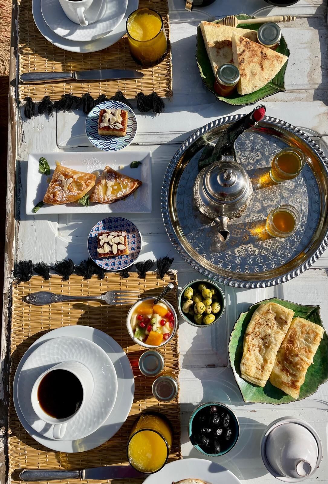 A breakfast spread on a table with various dishes, including pastries, fruit, and beverages.