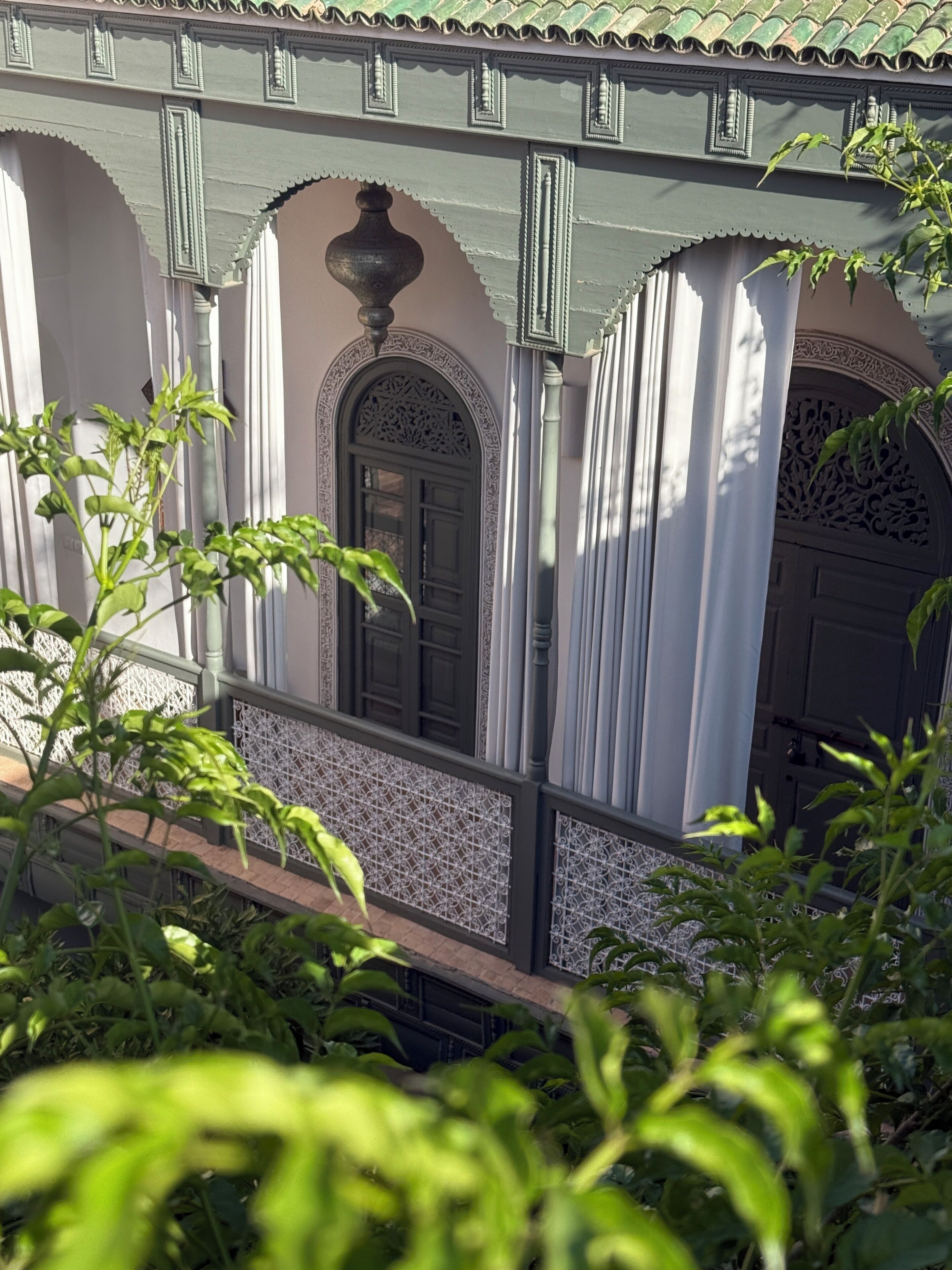 A traditional building with arched doorways, a balcony with a railing, and decorative metalwork.