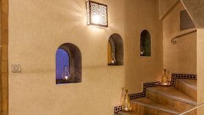 Una escalera con un diseño de baldosas estampadas, un aplique de pared y vistas a través de un ventanal de arco.