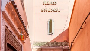 Un estrecho callejón con grandes macetas, una puerta tradicional y un edificio con tejado de tejas.