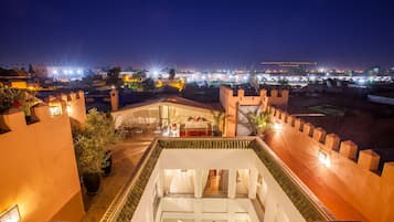 Une cour comprenant un espace repas, une piscine et offrant une vue sur le paysage urbain la nuit.