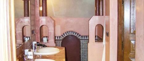 Un baño con dos lavamanos, un espejo y una pared con azulejos.