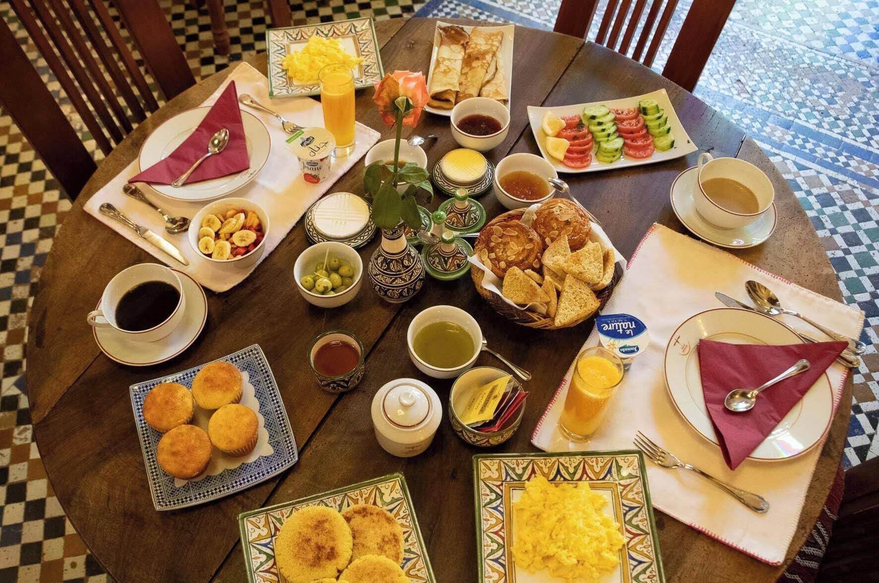 Un desayuno con diferentes platos, como huevos, pasteles y fruta.