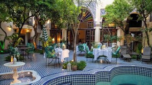 Un espace extérieur aménagé pour les repas, avec des tables et des chaises, une fontaine et une piscine.