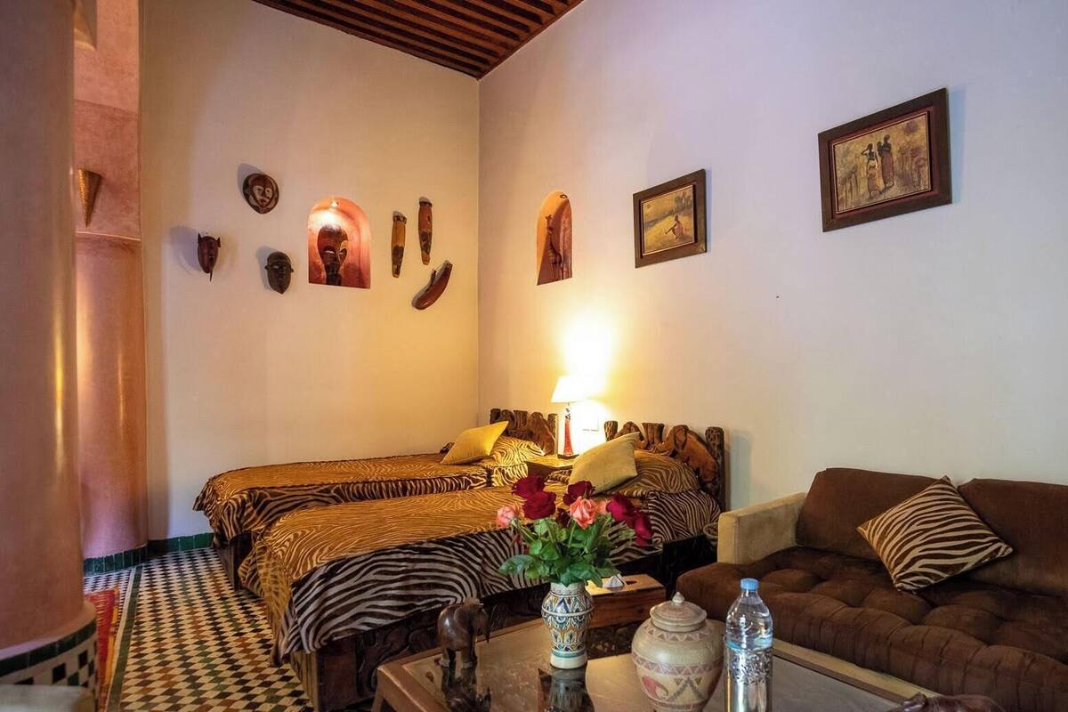 Ein Zimmer mit einem Bett, einem Sofa, einem Tisch mit Blumen und Wandbildern.