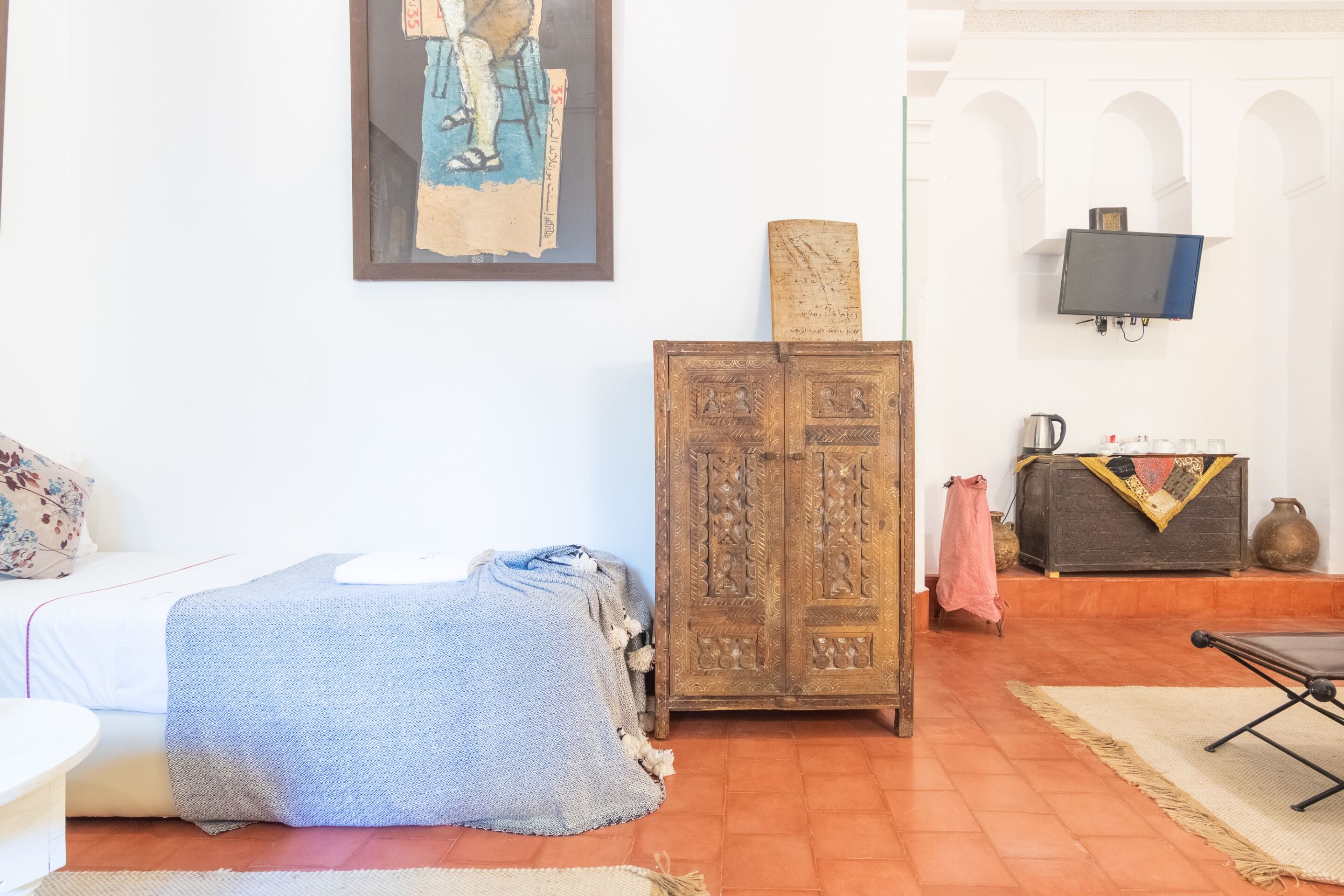 A room with a bed, a wooden cabinet, a television, and a sofa.